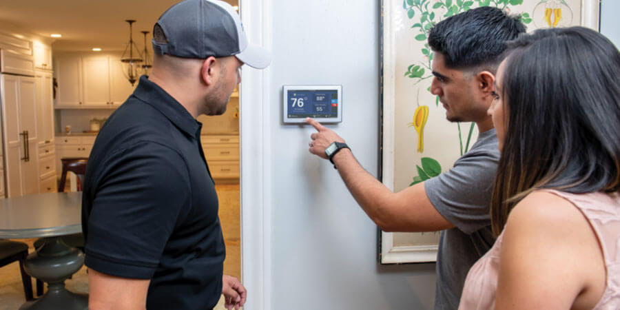 technician talking with customers about thermostat