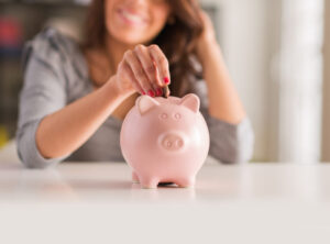 Woman Putting Change In Piggy Bank