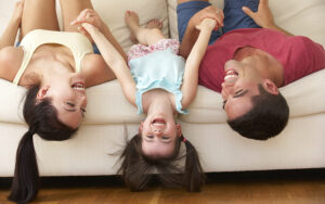 Happy Family Lying Upside Down On Couch