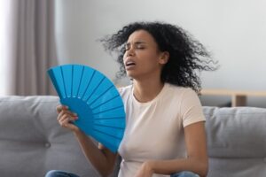 Woman Fanning Herself Sitting On Couch