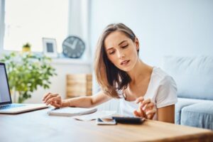 Woman Doing Math At Living Room Coffee Table