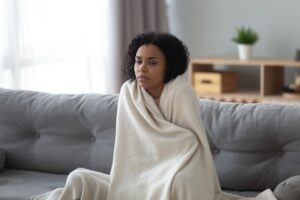 Tired Woman Wrapped In Blanket On Couch